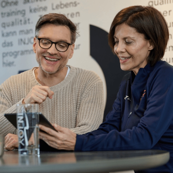 INJOY Mitglied in einem Betreuungsgespräch mit einer Trainerin am iPad.