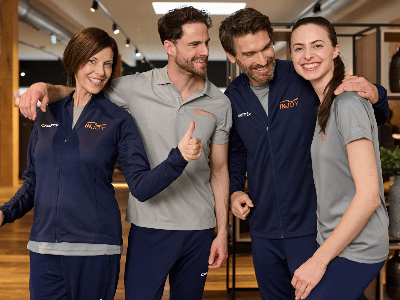 Vier INJOY Trainer stehen nebeneinander und lachen in die Kamera.