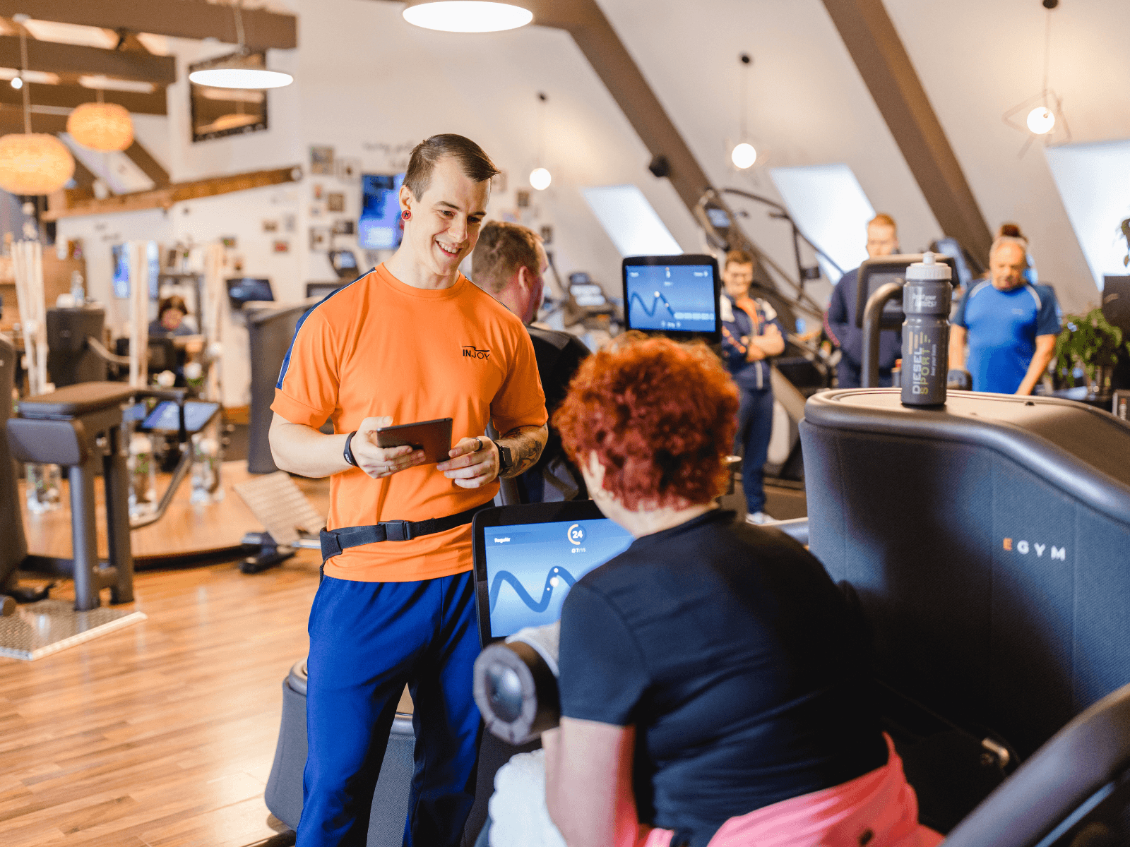 Ein Trainer im INJOY Fitnessstudio Steyr beantwortet die Fragen eines Mitglieds beim Training