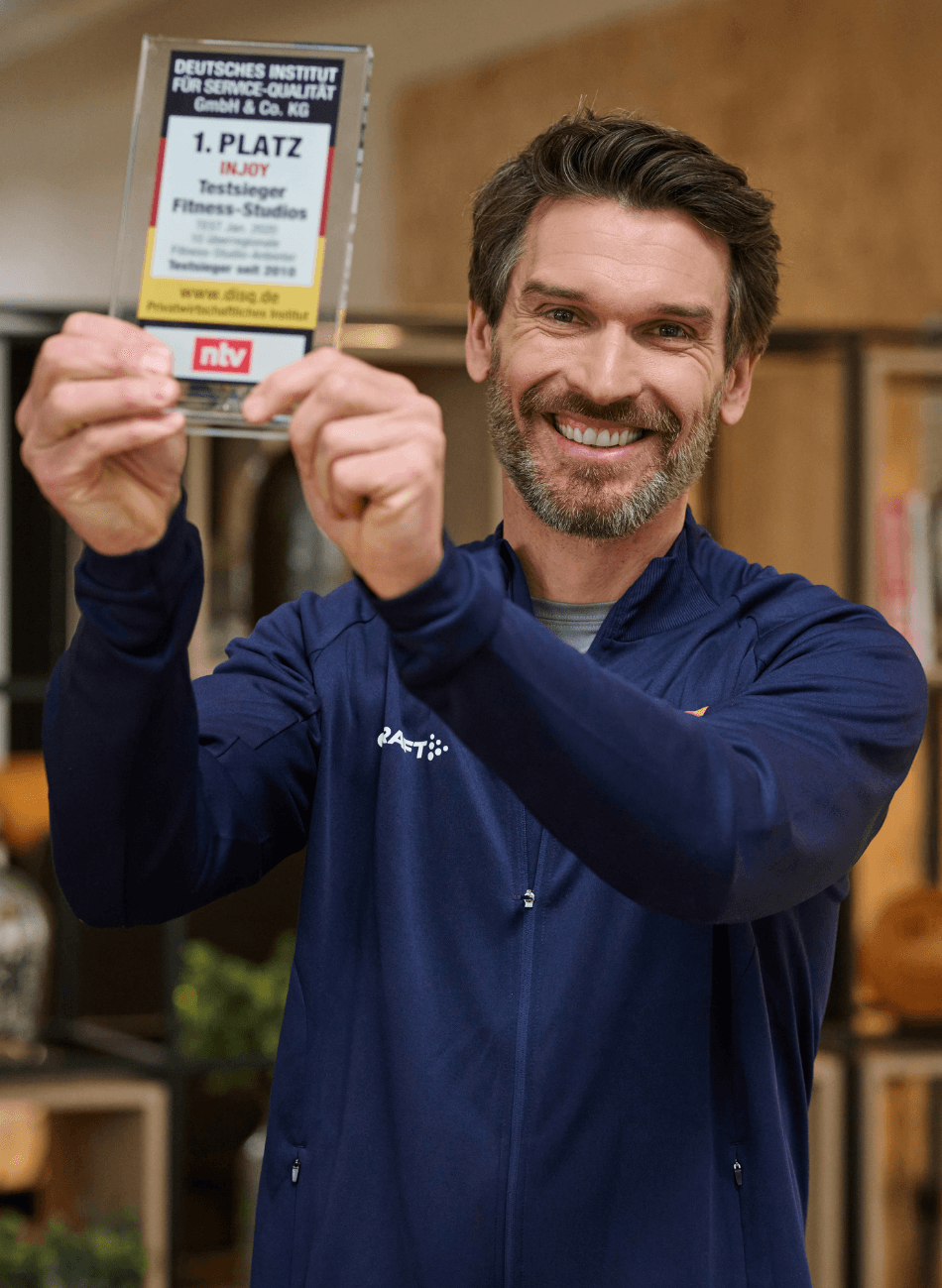 Ein stolzer INJOY Trainer präsentiert die Auszeichnung zum 1. Platz für Service und Beratung.