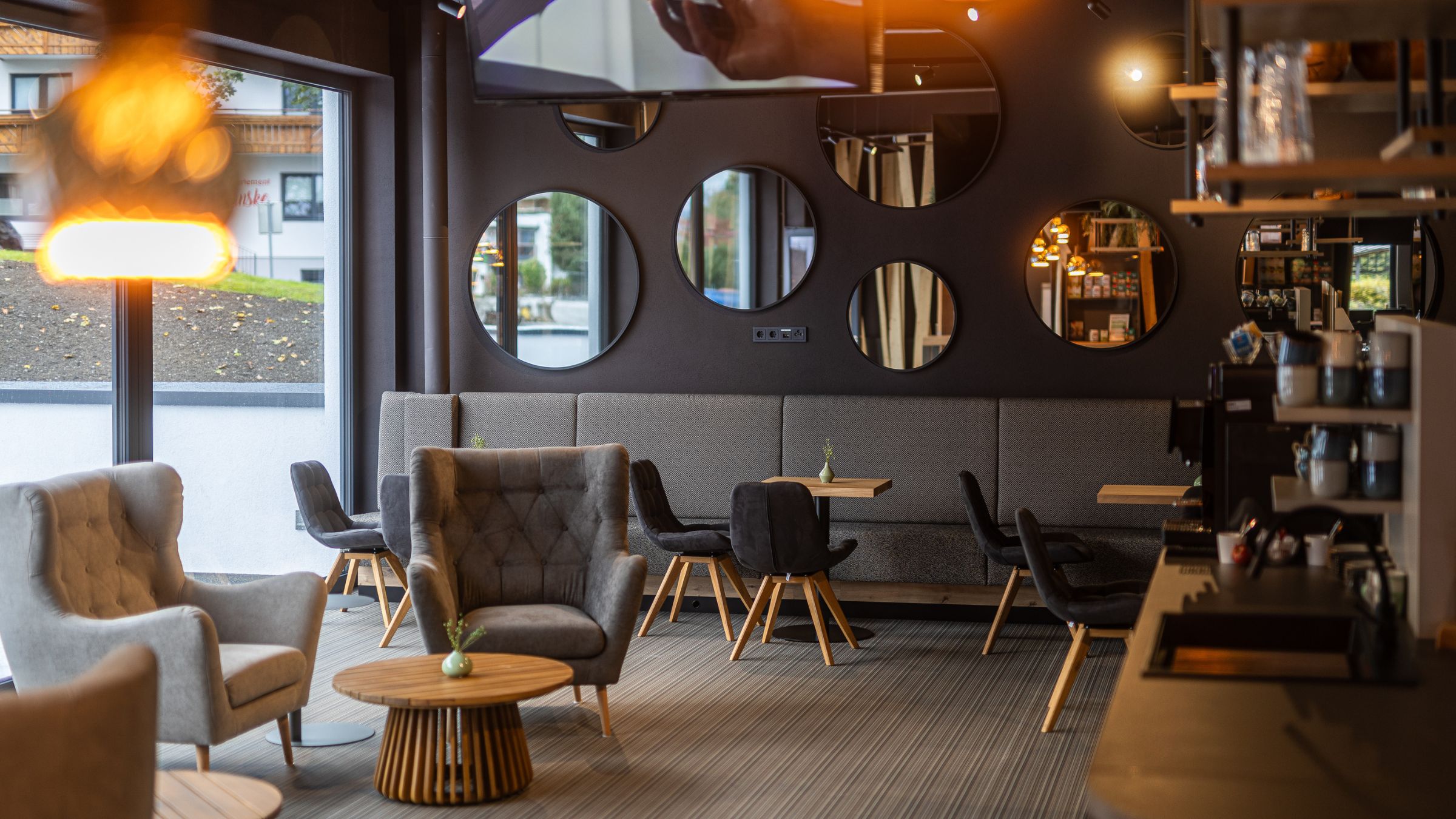 Lobby mit Sesseln, Tischen und Stühlen im INJOY Fitnessstudio Kaprun.