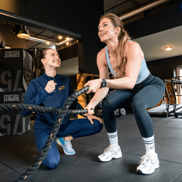 Junges Mitglied trainiert an Battle Ropes und wird dabei von INJOY Trainerin motiviert.