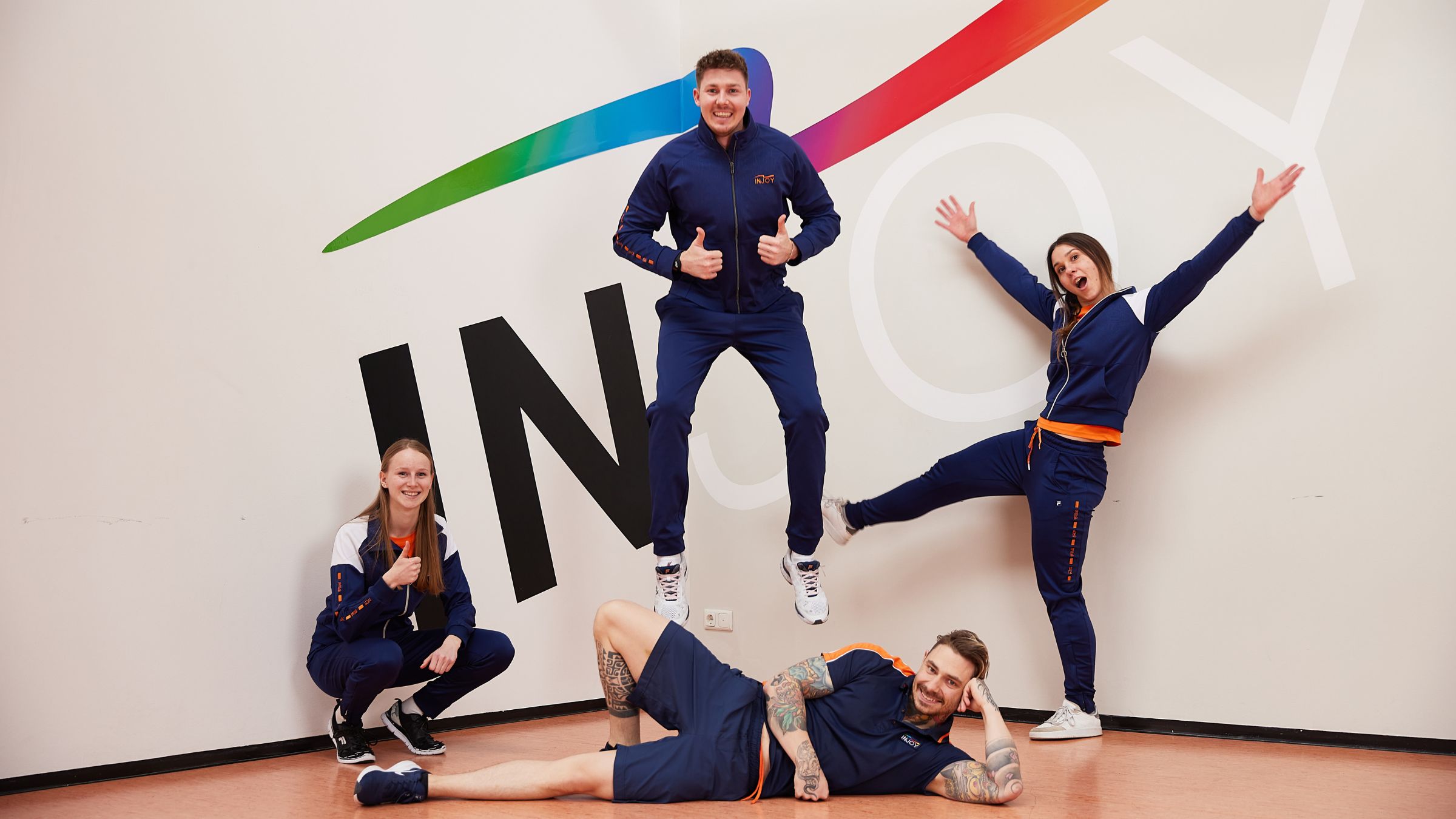 Ein Gruppenfoto im INJOY Fitnessstudio Bregenz, in die vier Mitarbeiter verschiedenen Posen machen.