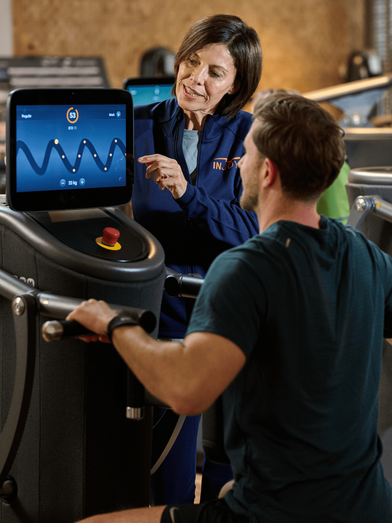 Eine INJOY Trainerin erklärt einem Mitglied das Training an einem EGYM Gerät