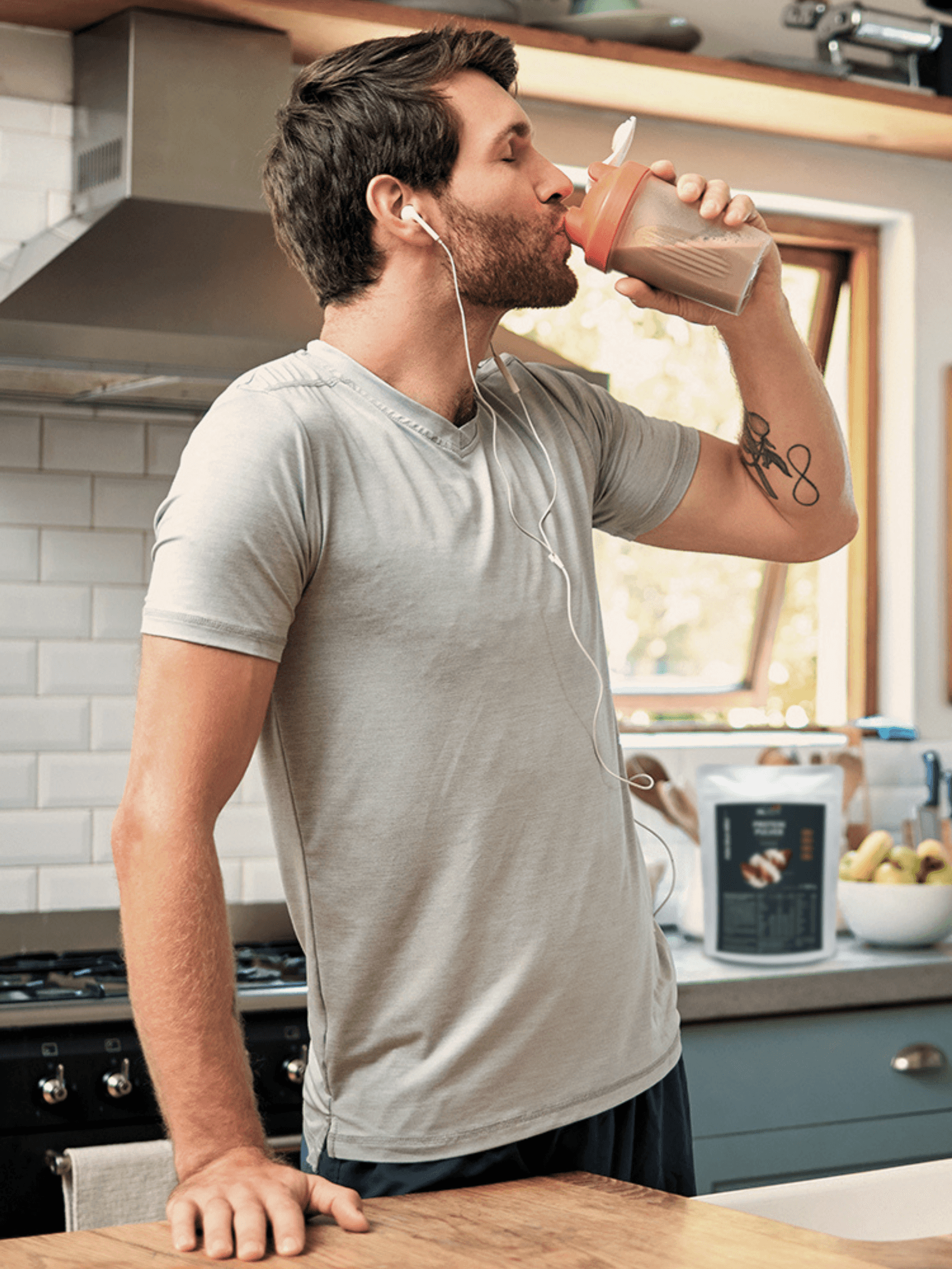 Ein männliches INJOY Mitglied genießt zu Hause in der Küche einen INJOY Nutrition Shake.