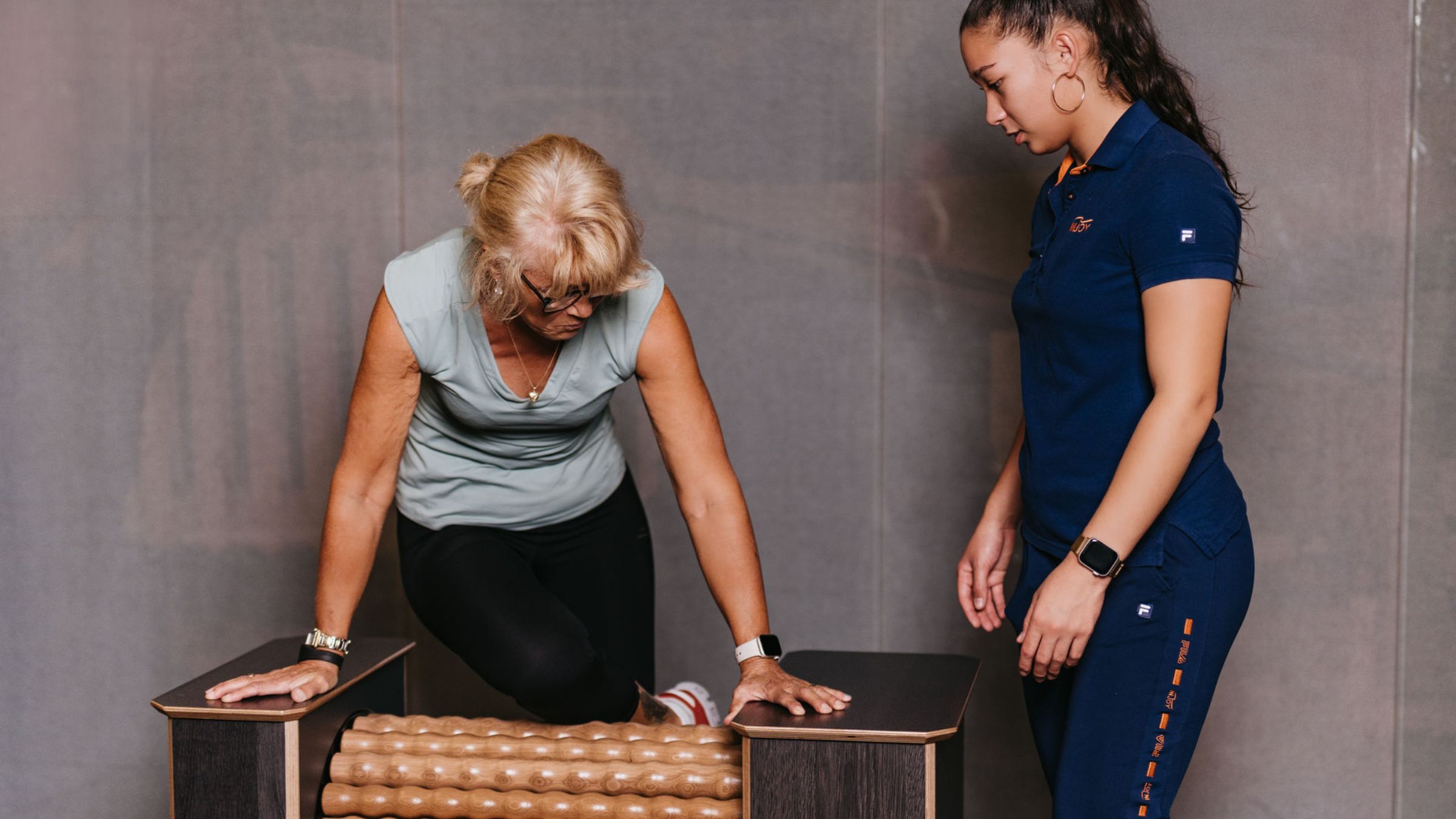 Eine Trainerin betreut eine Frau bei der Faszien- und Massagerolle im INJOY Fitnessstudio Eferding.