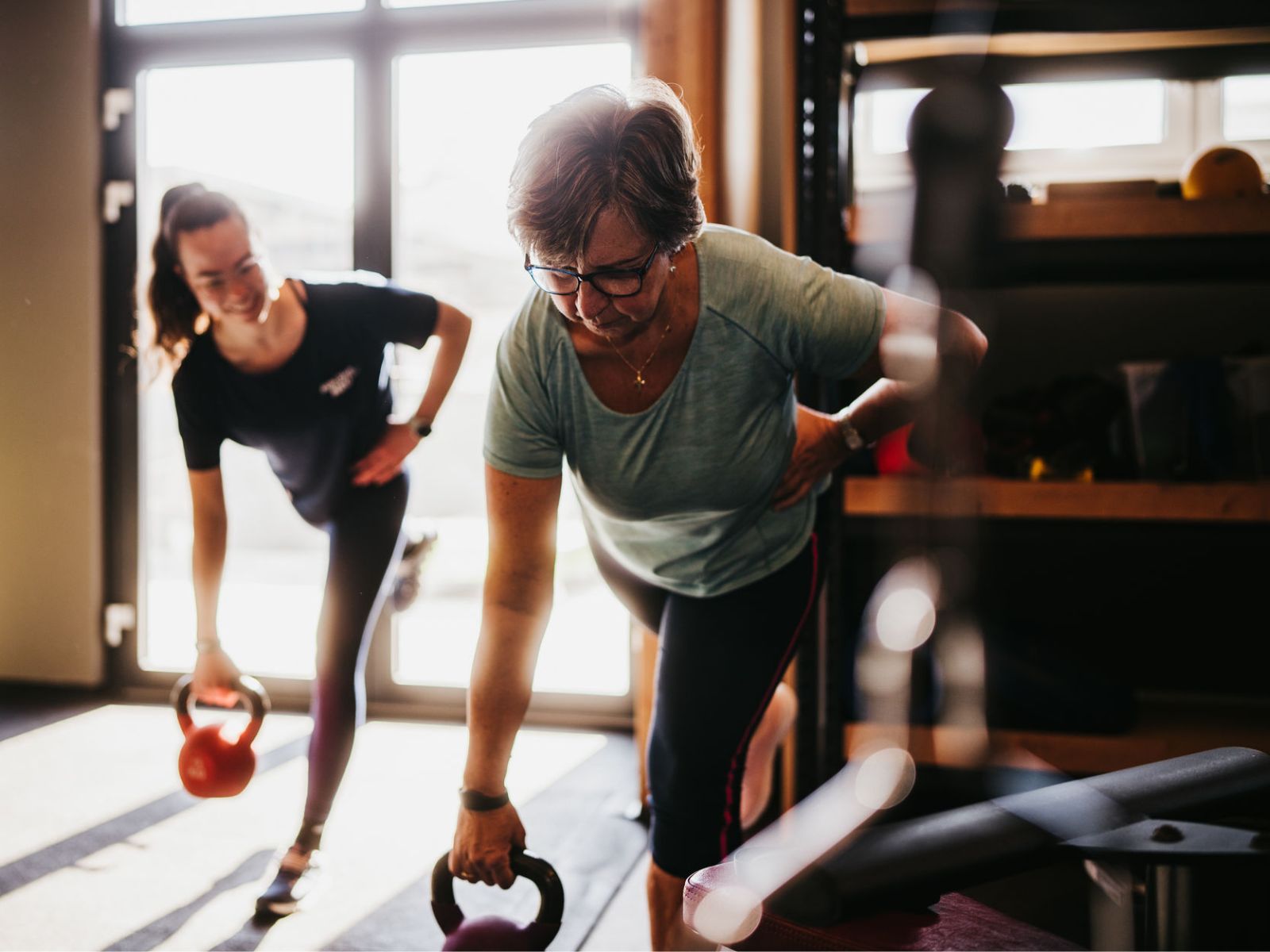 Eine Personaltrainerin betreut eine Frau bei einer Übung mit Kettlebell im INJOY Fitnessstudio Eferding.