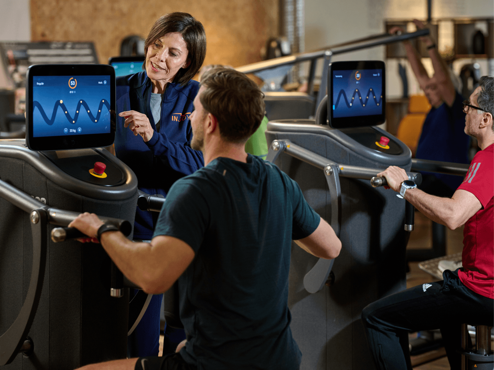 Eine INJOY Trainerin weist ein junges Mitglied in die Brustpresse des elektronischen Zirkels ein.